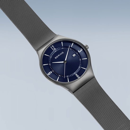 Grijs BERING horloge met blauwe wijzerplaat en zilverkleurige wijzers, mesh band.