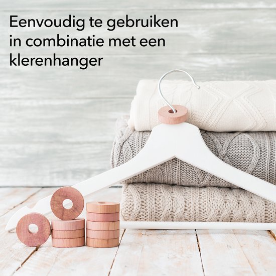 Cederhouten ringen op een kledinghanger met een stapel gebreide kleding.