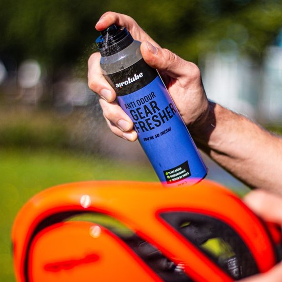 Hand spuit Airolube Anti Odour Gear Freshener op een oranje fietshelm.