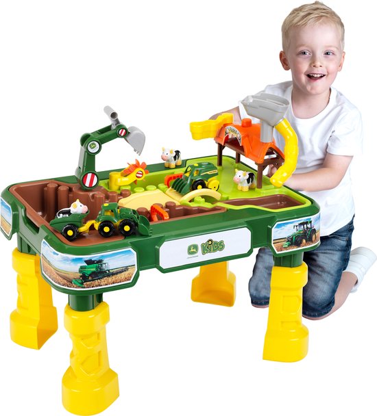 Een jongen speelt met een John Deere boerderij speeltafel met tractoren en dieren.