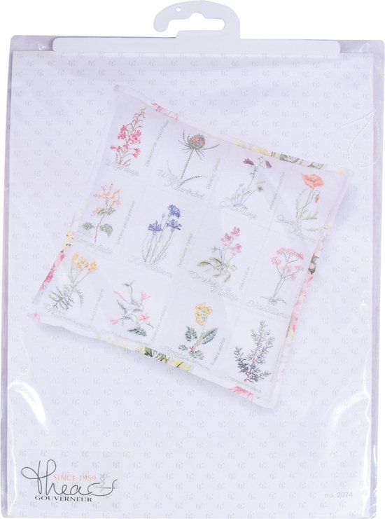 Emballage avec un coussin présentant des broderies en point de croix de fleurs sauvages.