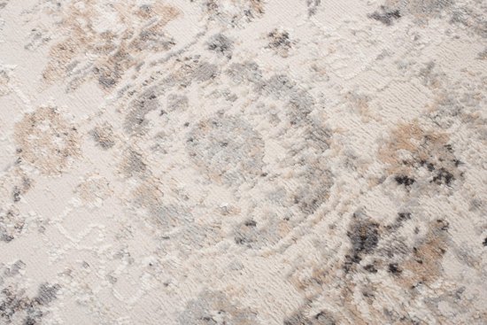 Gros plan d'un tapis gris clair aux motifs discrets et délavés dans des tons gris et beige.