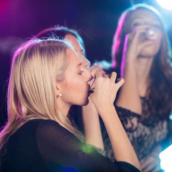 Vrouwen met blond en bruin haar nippen aan glazen, met sfeerverlichting.