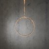 Une guirlande lumineuse circulaire avec des lumières LED blanc chaud est suspendue devant un mur en béton.