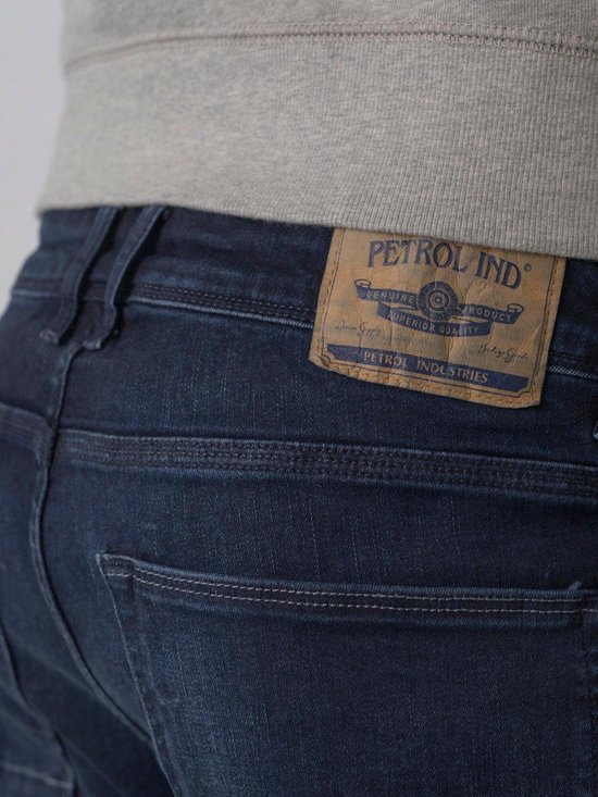Detail van het bruine leren Petrol Industries label op de achterkant van een donkerblauwe jeans.