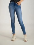 Model draagt een skinny spijkerbroek met hoge taille, blauwe denim met lichte wassing en rafelige zoom.