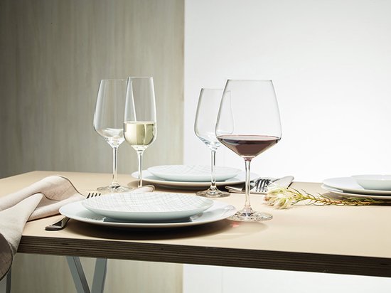Table dressée avec des verres à vin remplis de vin rouge et blanc, et des flûtes remplies de champagne.