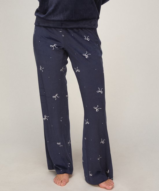 Donkerblauwe velours pyjamabroek met strikje print, gedragen door een model.