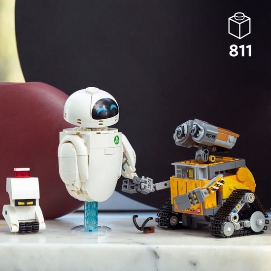 Trois robots LEGO : un petit blanc, EVE et WALL-E, ce dernier sur chenilles avec des détails jaunes et gris, se serrant la main.