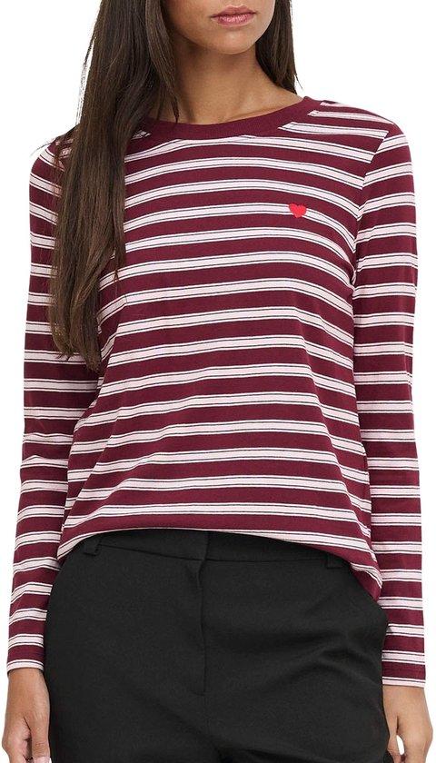 Model in gestreept shirt met lange mouwen, bordeauxrood met roze strepen en een rood hartje op de borst. Gedragen met zwarte broek.