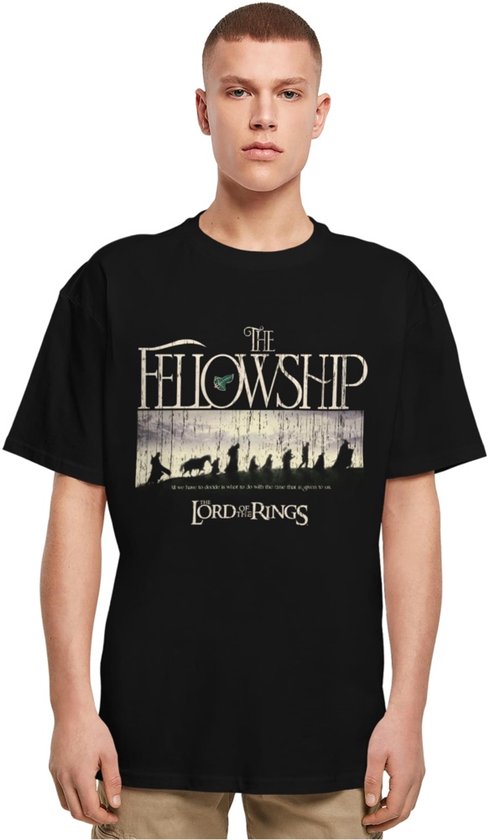 Man met blond haar draagt zwarte T-shirt met 'The Fellowship of the Lord of the Rings' print.