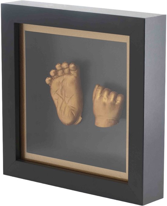 Main et pied de bébé dorés dans un cadre noir avec une bordure dorée, dans une composition épurée.