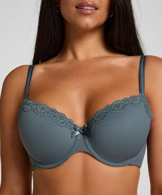 Close-up van een donkerblauwe, geribbelde beugelbeha met kanten rand en strikje op het model.