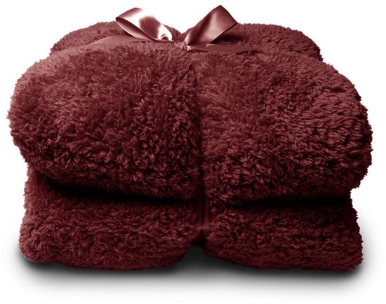 Bordeauxrode teddy plaid, opgevouwen en vastgebonden met een satijnen lint.