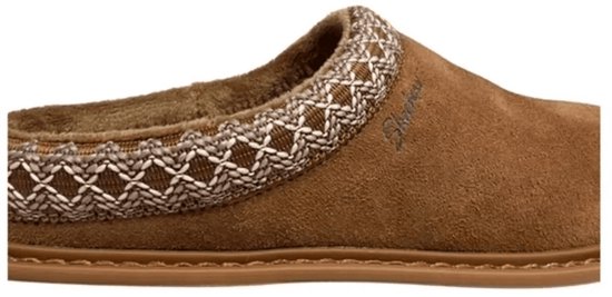 Close-up van een bruine suède slof met het Skechers-logo en een beige, kruislings geweven boord.