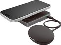 Donkergrijze magnetische powerbank verbonden met een oplaadpad, naast een smartphone in een witte behuizing.