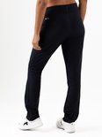 Achterkant van een model in een donkerblauwe stretch trainingsbroek met witte sneakers.