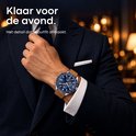 Man in pak draagt een blauw horloge met bruine band. Tekst: 'Klaar voor de avond. Het detail dat je outfit afmaakt.'