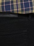 Close-up van de achterkant van zwarte jeans met een geruite blouse.
