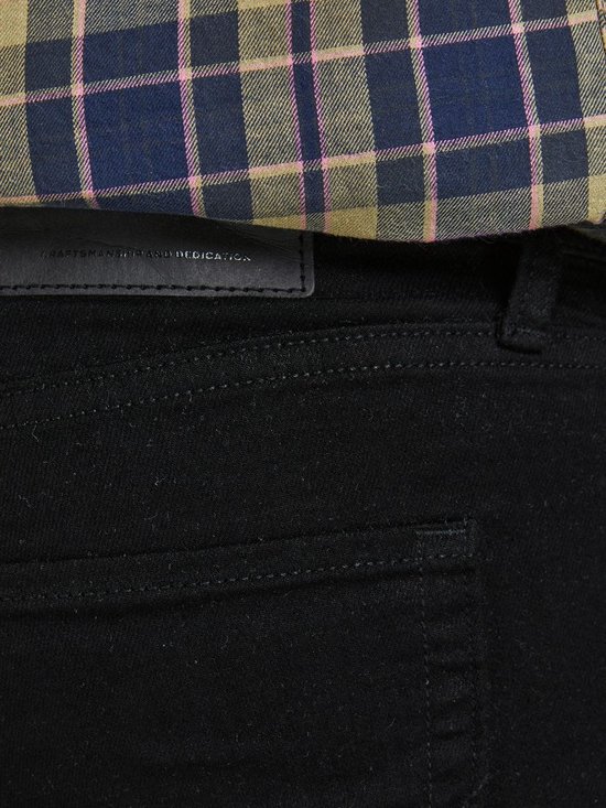 Close-up van de achterkant van zwarte jeans met een geruite blouse.