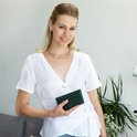 Vrouw met witte top en gouden ketting houdt groene leren Selencia bookcase vast.