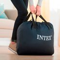 Vrouw met spijkerbroek en sneakers draagt een donkerblauwe Intex draagtas.