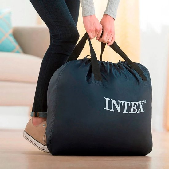 Vrouw met spijkerbroek en sneakers draagt een donkerblauwe Intex draagtas.