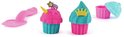 Twee glitter cupcakes, een met unicorn hoorn, de ander met een kroon. Roze en blauwe bakvormen en gereedschap.
