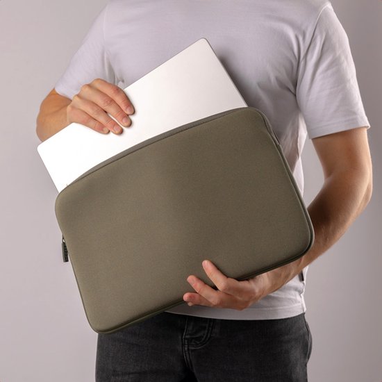 Een man in een wit T-shirt houdt een groene laptoptas vast waarin een witte laptop wordt geschoven.