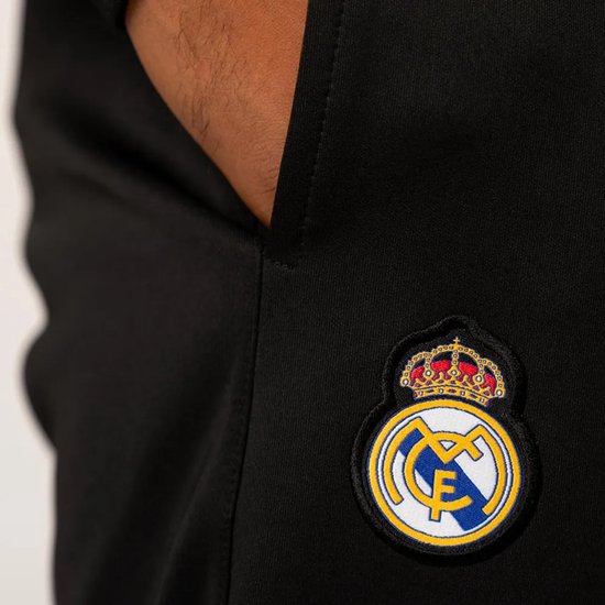 Detail van zwart trainingsbroek met geborduurd Real Madrid logo op de heup.