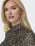 Close-up van een model met blond haar, draagt een mesh coltrui met panterprint.