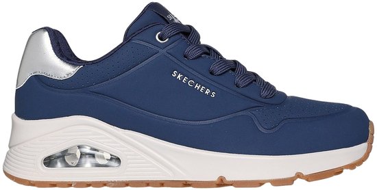 Donkerblauwe sneaker met crèmekleurige zool, zilveren detail op de hiel en "SKECHERS" opdruk.