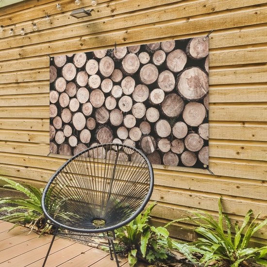 Une affiche avec des bûches empilées de différents diamètres et teintes naturelles, accrochée à une clôture en bois.