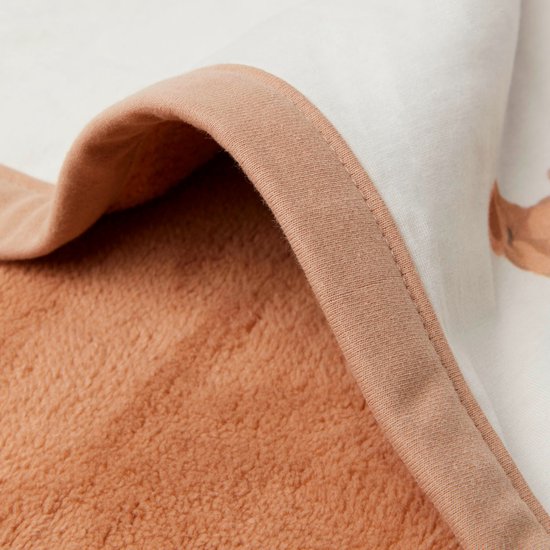 Gros plan de la doublure douce en polaire marron d'une couverture pour bébé avec une couche de coton blanche à imprimé ours en peluche.