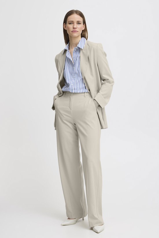 Mannequin portant un pantalon crème à jambes larges, un chemisier rayé et un blazer beige.