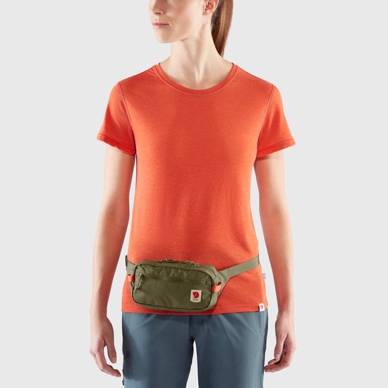 Groene heuptas gedragen door een vrouw, op de heup, met een ritsvak en oranje accenten.