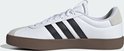 Witte leren Adidas sneaker met zwarte strepen en bruine zool.