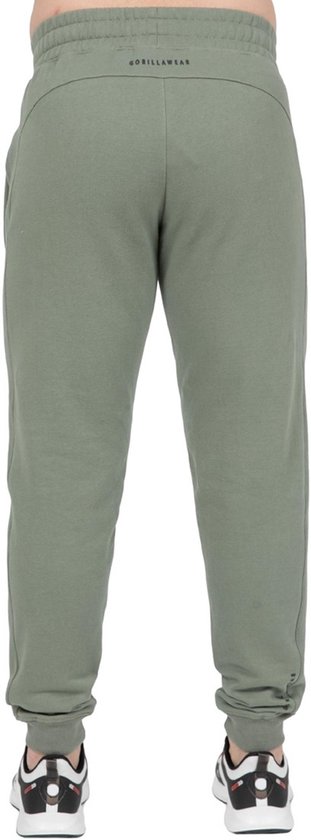 Achterkant van man in groene joggingbroek met 'GORILLAW EAR' op de rug.