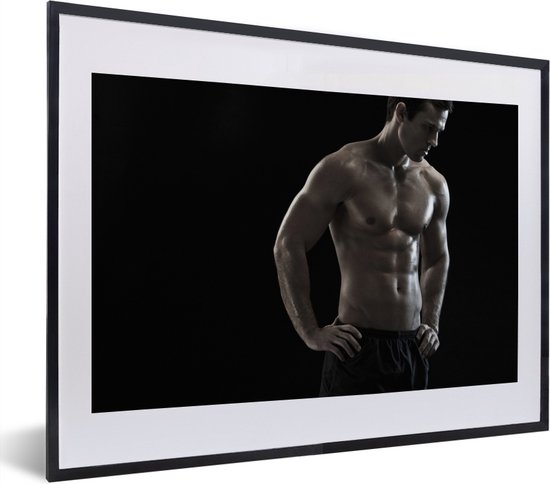 Une affiche noir et blanc d'un homme musclé, mains sur les hanches, regardant vers le bas, sur fond noir.