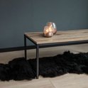 Salontafel met licht houten blad en zwart stalen frame. Twee glazen windlichten met kaarsen erop.
