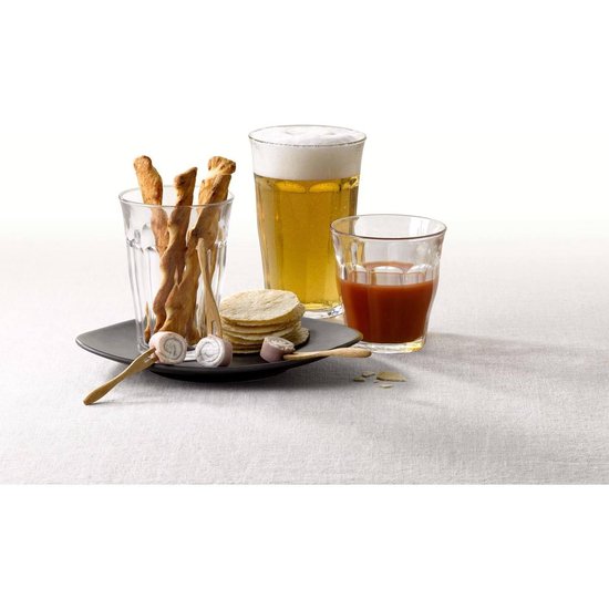 Trois verres Duralex, un avec de la bière, un avec une boisson rouge, un avec des toasts et des roulés.