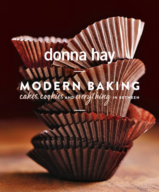 Boek met de titel 'donna hay MODERN BAKING cakes, cookies en alles daartussen', gestapelde bruine cupcakevormpjes.