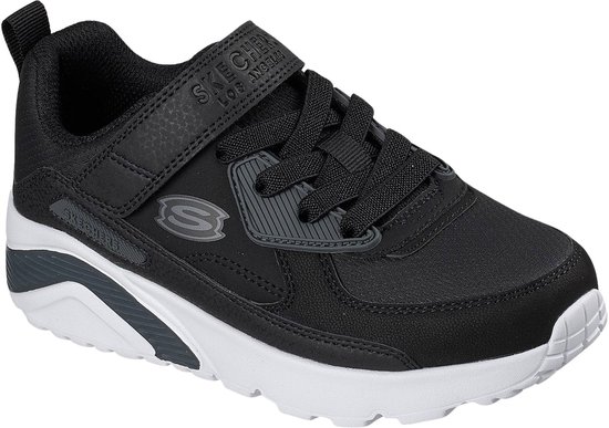 Zwarte sneaker met klittenbandsluiting, veters, witte zool en grijze details.