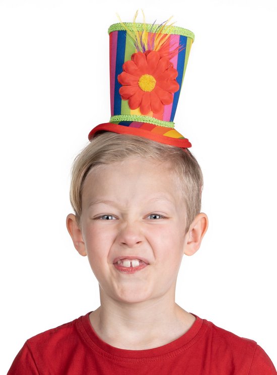 Jongen met blond haar die een rode T-shirt draagt en met zijn gezicht vertrekt met een veelkleurige clownshoed met bloem.