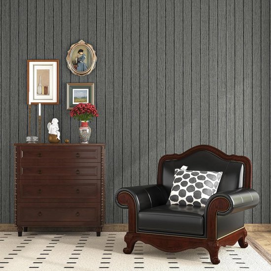 Papier peint à grain de bois gris foncé dans une chambre avec un fauteuil en cuir marron et une commode.