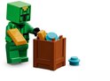 Groen LEGO Minecraft figuurtje met een gouden staaf en een bruine kist met LEGO onderdelen.