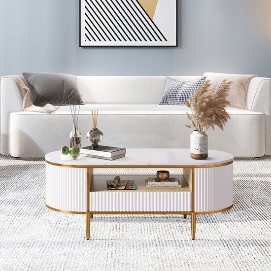 Ovale salontafel met marmerlook blad, wit geribbeld design en gouden poten. Met open vakken en een lade.