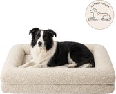 Zwart-wit hond ligt op een beige bouclé orthopedisch hondenkussen.