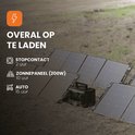 Zwarte powerstation op gras naast zonnepanelen. "OVERAL OP TE LADEN". Laadtijd via stopcontact: 2 uur.