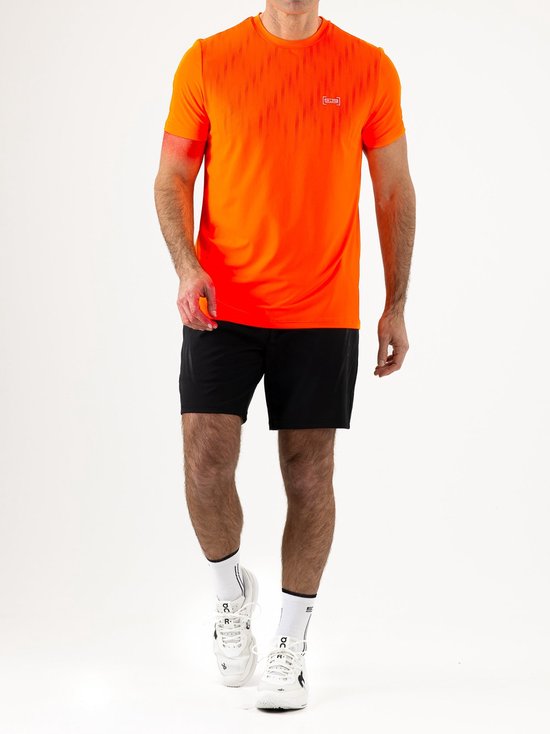 Man in een feloranje sportshirt met streepjespatroon en zwart sportbroekje, witte sportsokken en schoenen, lopend.